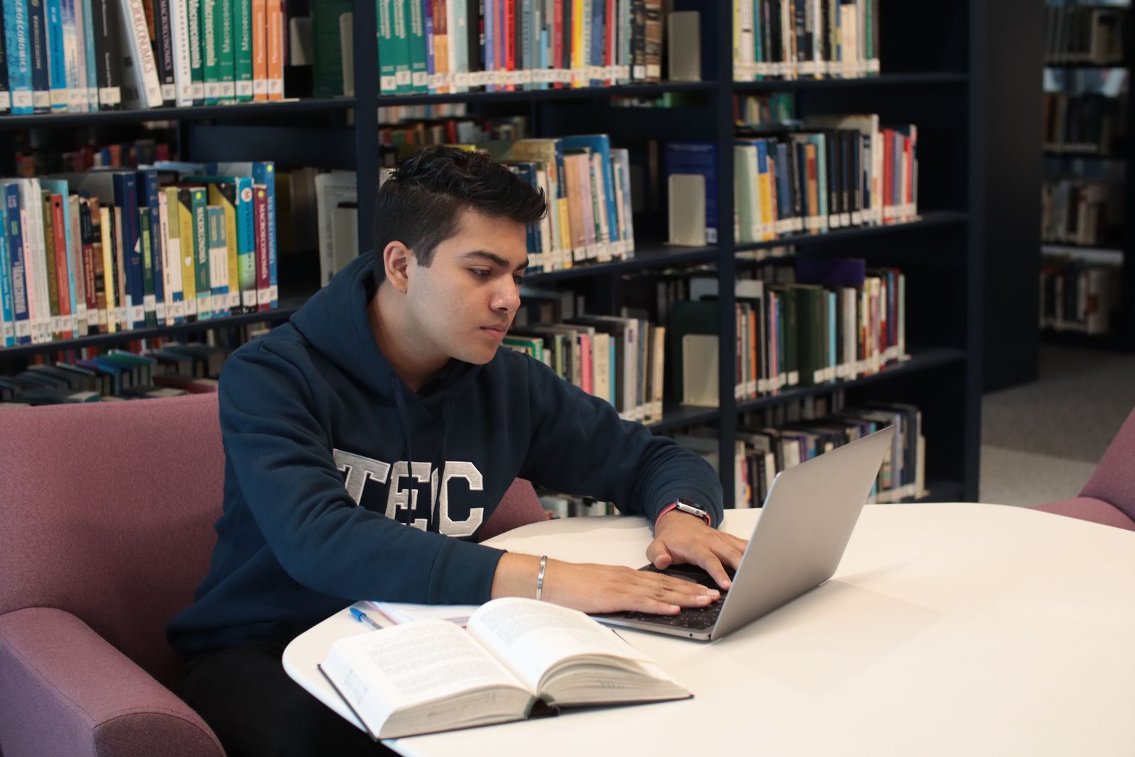 Library research with a laptop and open textbooks