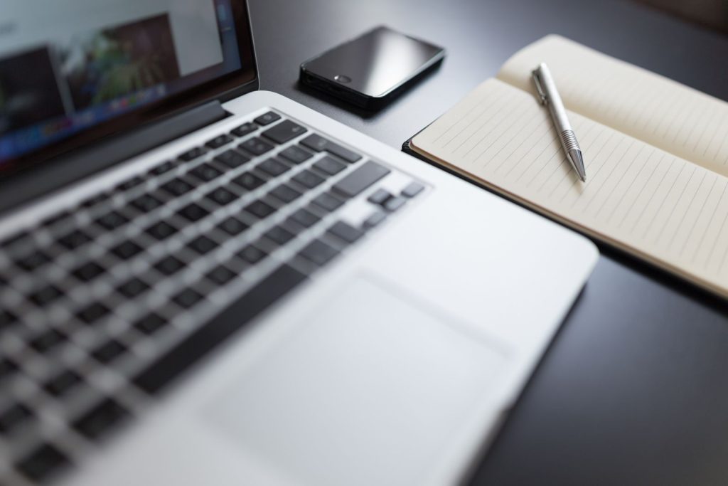 Laptop, notebook and smartphone arranged on a desk